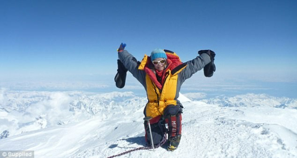 Katie Sarah on top of a mountain peak with nothing but snow around her