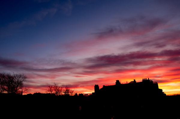 A landscape-oriented colour photograph of the sky over Edinburgh tonight.

At the bottom of the picture is the silhouette of the skyline from my flat looking south-south-west, with the tenement opposite  filling most of the bottom right and the battlements of Edinburgh castle visible at the bottm left.

Above that, the sky is coloured, ranging from orange near the bottom (to the right of the tenement), through deep red and mauve clouds; other cloudss are dark grey. Where there are no clouds the sky is various shades of blue, from palid blue low down to dark intense blue-black in the top left.