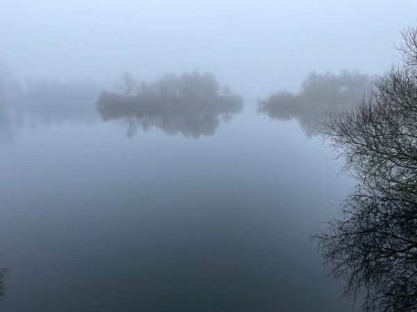 Photo of small island in a lake while weather is misty. 