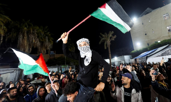 Un hombre ondea banderas palestinas festejando el acuerdo de alto el fuego con Israel, en Deir Al-Balah, en el centro de la Franja de Gaza, el 15 de enero de 2025. (Ramadan Abed / Reuters)