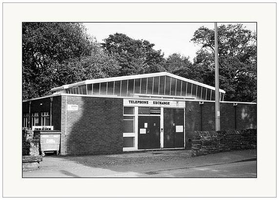 Black and white photograph showing an old telephone exchange building basking in the sunlight.