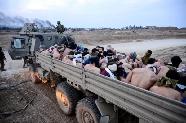 Israeli soldiers stand by a truck packed with shirtless Palestinian prisoners in Gaza in 2024 [File: Yossi Zeliger/Reuters]