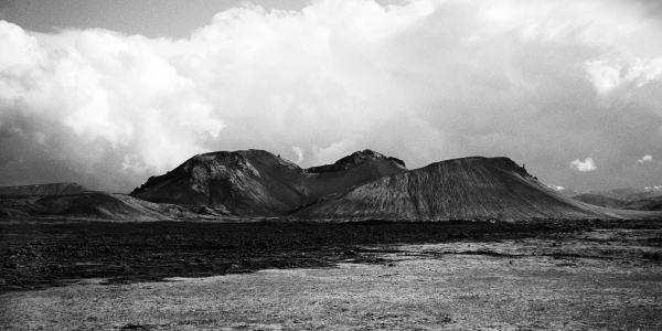 Vue d'un paysage volcanique constitué d'un cône de volcan et de plusieurs monts de lave.