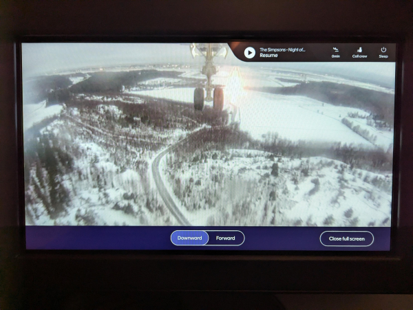 Photo of the external camera view displayed inside a Finnair A350 on approach to land at Helsinki. The front landing gear and a snowy forest can be seen.