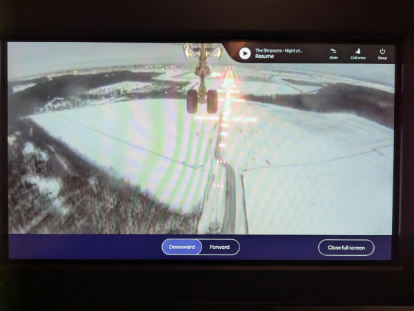 Photo of the external camera view displayed inside a Finnair A350 on approach to land at Helsinki. The front landing gear and the runway approach lights can be seen.