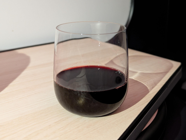 Photo of a glass of Finnish blueberry wine. It is a very deep red, like a ruby port.