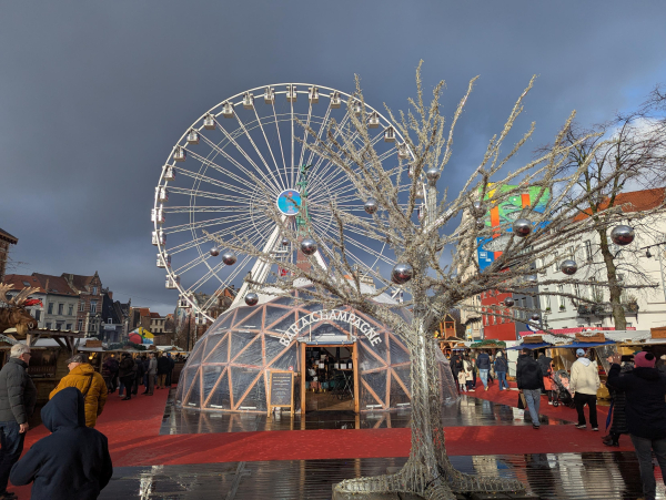 Photo of the Christmas markets in Brussels, showing a champagne bar inside a plastic dome, and a large Ferris wheel.