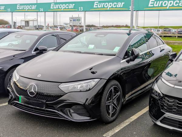 Photo of a shiny black Mercedes Benz EQE 350+ electric saloon car in a Europcar car park.