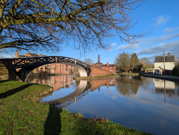 Photo of a cast iron footbridge over a canal basin. The bridge has the construction date of 1837 written on it, along with "Britannia Foundry Derby".