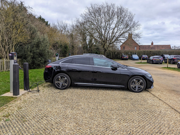 Photo of a Mercedes EQE from the side, parked in a charging bay, plugged into an AC charging post 