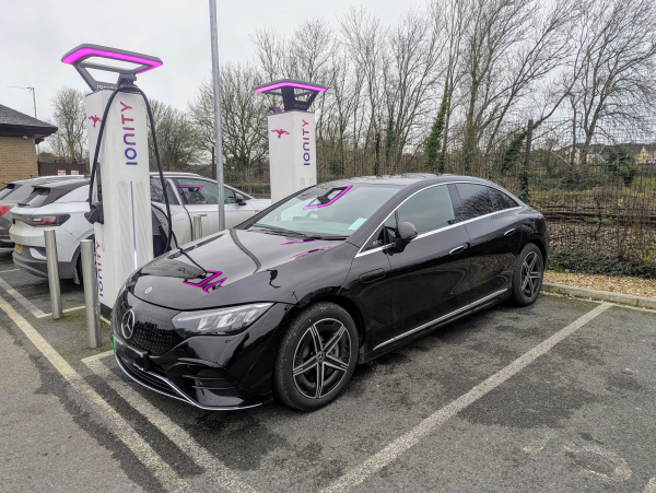 Photo of a Mercedes EQE parked next to a pair of Ionity chargers, which have glowing purple haloes.