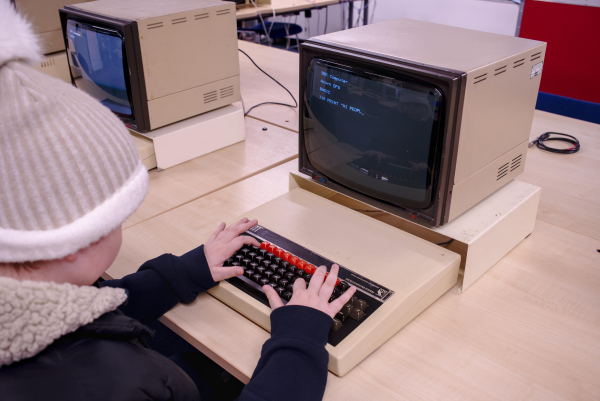 Photo of child typing on the keyboard of a 1980's BBC microcomputer with a CRT monitor.