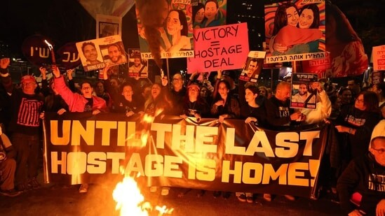 Israel-Hamas ceasefire live updates: People hold placards and light candles in front of a fire during an anti-government protest calling for action to secure the release of Israeli hostages held captive since the October 7, 2023 attacks by Palestinian militants in the Gaza Strip, outside the Israeli Defence Ministry in Tel Aviv on January 18, 2025, a day before a ceasefire approved by Israel and Hamas is set to take effect.