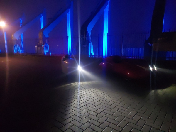 Auf dem Heimweg stehen unsere Velomobile im dunkeln vor den blau beleuchteten Kränen am Weserwehr. 