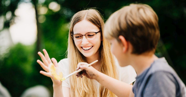 Studentische Mentorin malt mit einem Grundschüler