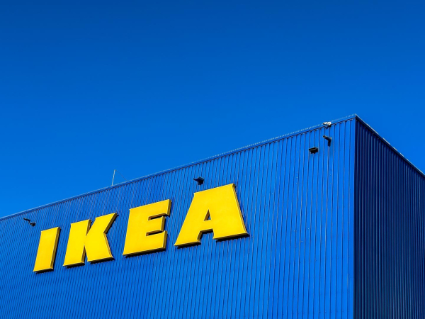 Blaues Ikea Gebäudeeck mit gelbem Schriftzug vor blauem Himmel.