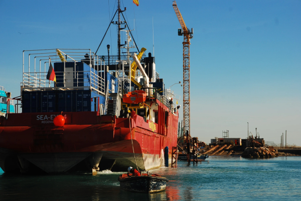 bild im querformat:
am heck des rettungsschiffes sea-eye 4 hängt ein kleines motorboot, welches versucht das heck in position zu ziehen für die einfaht ins trockendock