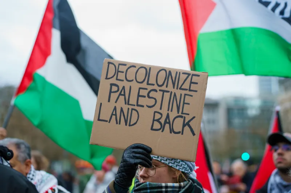 Palestinian flags and a sign saying "Decolonize" and "Palestine land back".