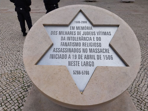 Ein runder Gedenkstein, in dem ein 6-eckiger Stern ausgespart wurde, in welchem auf spanisch an die Ermordung tausender Juden 1506 erinnert wird
A round memorial stone with a hexagonal star carved into it, commemorating in Spanish the murder of thousands of Jews in 1506