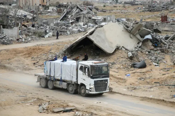 Palestinians secure an aid truck moving along a road after crossing into Gaza [File: Hatem Khaled/Reuters]