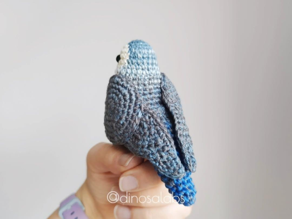 La misma foto del mismo agapornis en una postura similar a la anterior en la que se aprecia el amigurumis de espalda y el degradado de colores que este tiene