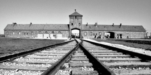 Eingangstor zum Lager Auschwitz-Birkenau. Man sieht die Eisenbahnschienen die in das Lager hinein führen. 