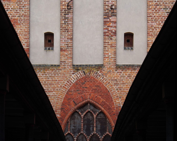 The east gable of a high medieval hospital church with two covered passageways built in the Baroque period, which allowed the gallery of the elderly and the wretched to reach a gallery of the church. Hatches and pointed arches form a face.