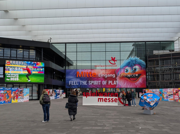 Eingang einer Messehalle mit Werbung und Beschriftung «Spielwarenmesse» und «The spirit of play»