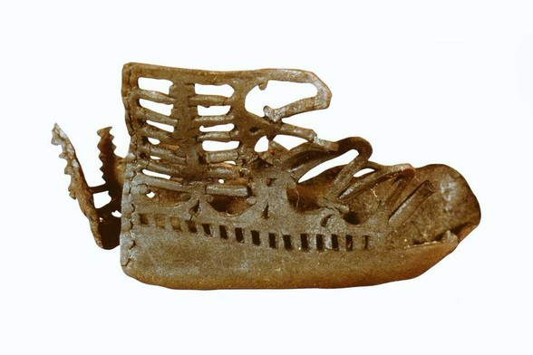 A well-preserved Roman leather shoe with elaborate cutout patterns. The design features a high ankle and open sections.