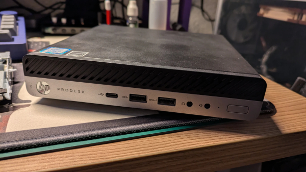 Ein HP ProDesk G3 Mini PC / in einem ca. 1 Liter großem Gehäuse. Oben schwarz - die Front oben Schwarz und unten silbern. Es sidn zwei USB Ports, ein USB-C Port und zwei HEadphone / Micro Anschlüsse zu sehen... und ein An/Aus Schalter