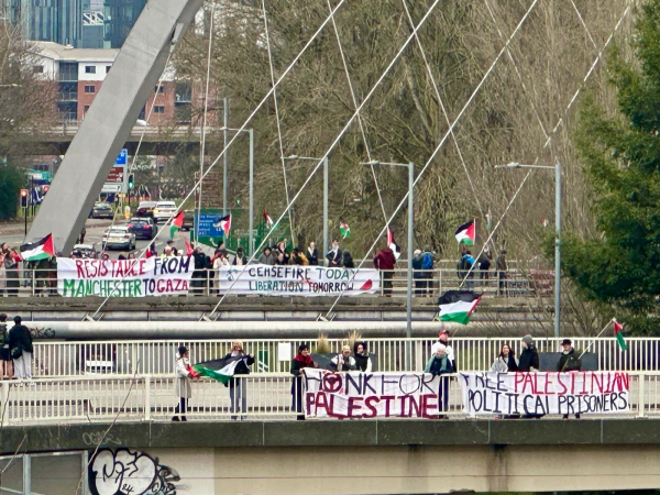 Pro-Palestine protester putting up banners and displaying Palestinian flags, Hulme Arch, Manchester, England.