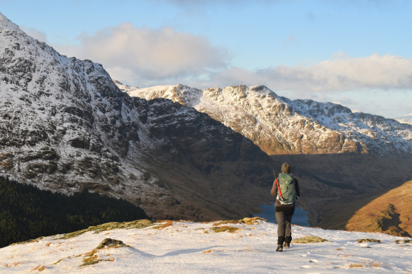 woman on snowy mountain, looking down at loch and mountains