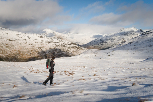 woman walking across snow with mountains behind