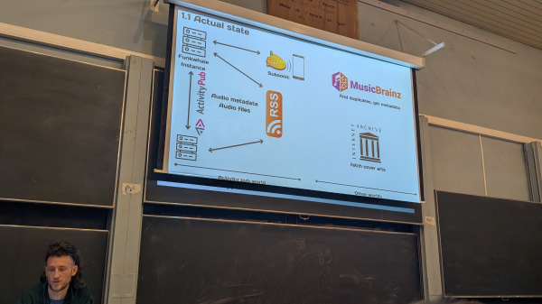 Person talking about the Fediverse's Funkwhale metadata scraping at a lectern with a screen showing the data flow