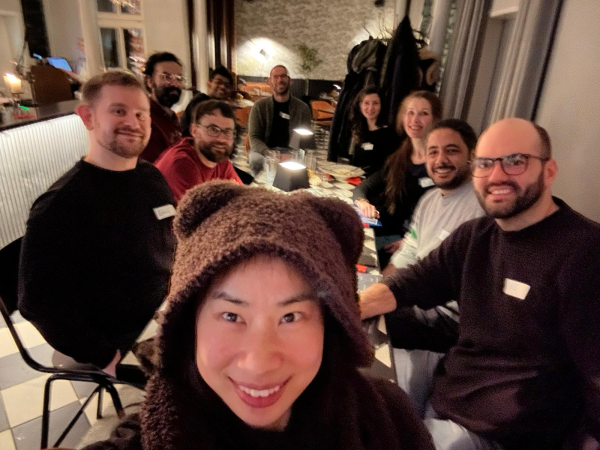 Image shows selfie taken by Dr Dingsu Feng (at the front) in brown furry hoody. It is taken in a cafe bar and there are a small group sitting at a table at a social event for researchers. This was the first postdoc social of 2025 and the traffic was stuck. Everyone had walked through heavy snow to get there. 