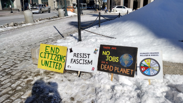 Protest signs in the snow, near a sidewalk.
1. End Citizens United
2. Resist Fascism
3. There are No Jobs on a Dead Planet
4. Climate Change Weather Wheel