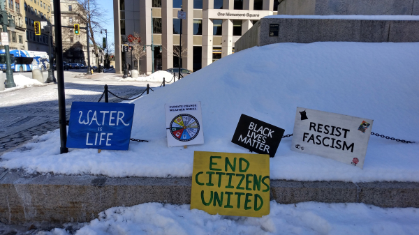 Protest signs in the snow, near a sidewalk, at the base of a statue.
1. Water Is Life
2. Climate Change Weather Wheel
4. Black Lives Matter
4. End Citizens United
5. Resist Fascism
