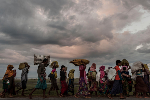 A group of people carrying items on their head walking in the same direction