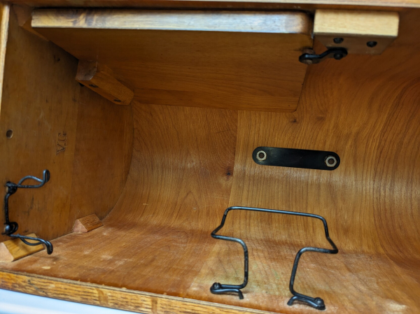 Looking inside the bentwood case, you can see the black metal strap securing the handle from the underside, the tiny table flap secured to the inside of the case, and two wire frames for holding accessories in storage.