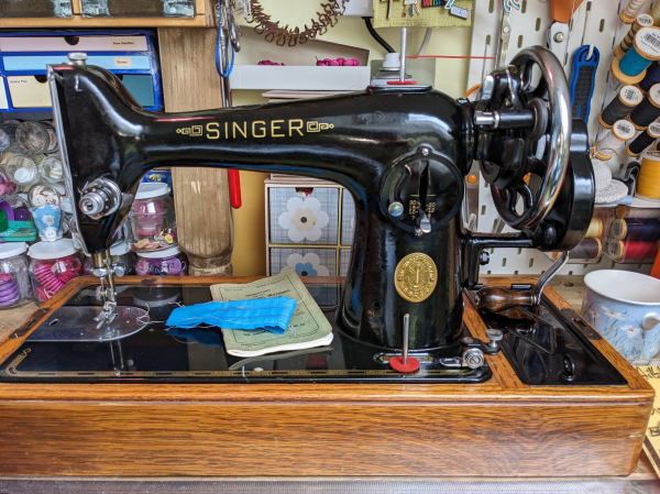 The uncovered sewing machine, gleaming black and gold and shining wood. It's really elegant, curved lines and very 1930s in shape.