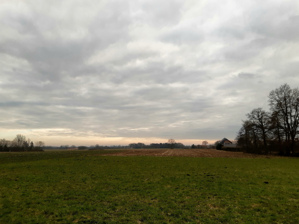 Bewölkter Himmel über den Feldern. Schmaler heller Streifen Sonnenlicht 