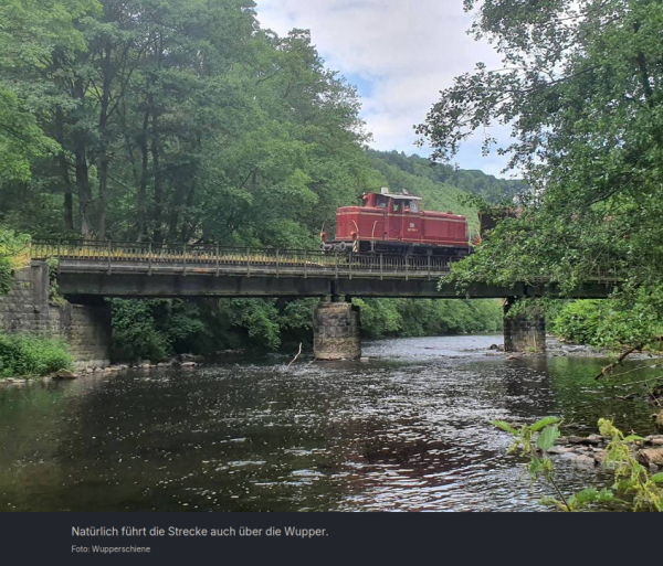 "Natürlich führt die Strecke auch über die Wupper."
Foto: Wupperschiene 

Eine rote Lokomotive fährt auf einer Brücke über die Wupper