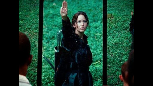 Katniss raising her hand in the iconic three-finger salute.