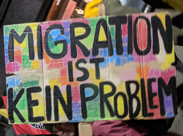 Buntes Demo-Schild mit der Aufschrift "Migration ist kein Problem"