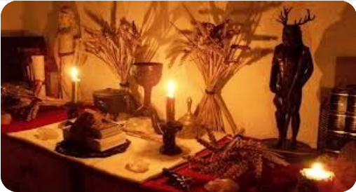 A ritual altar for Lughnasadh/Lammas, with candles, wheat sheaths, and a statue of a figurine with horns.