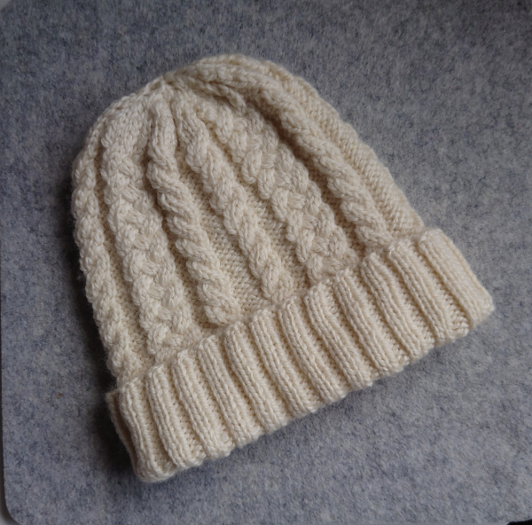 A cream cable knit hat with deep chunky rib rim knit in an Aran weight