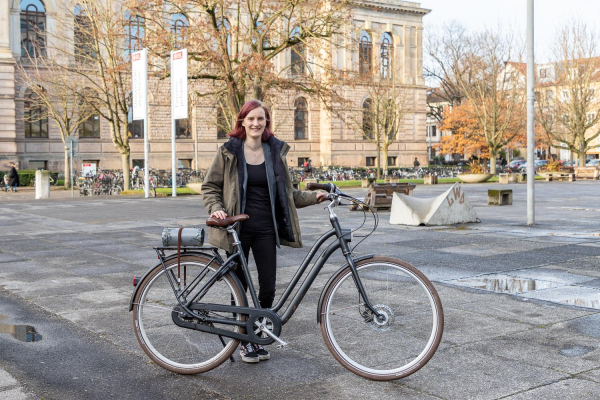 Merle Riecke steht mit ihrem Fahrrad vor dem Altgebäude der TU Braunschweig.

Foto: Kristina Rottig/TU Braunschweig