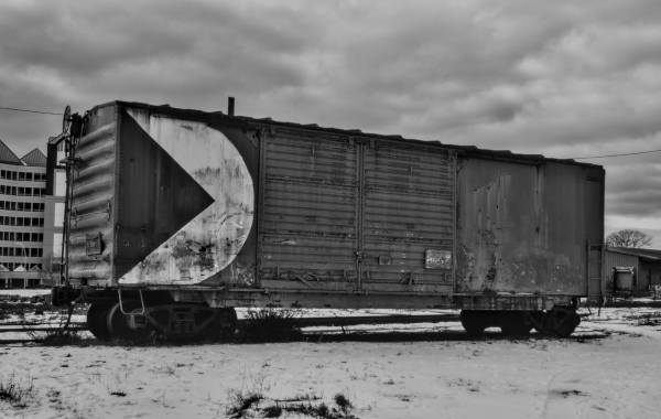 Old box car on track with light snow on the ground.