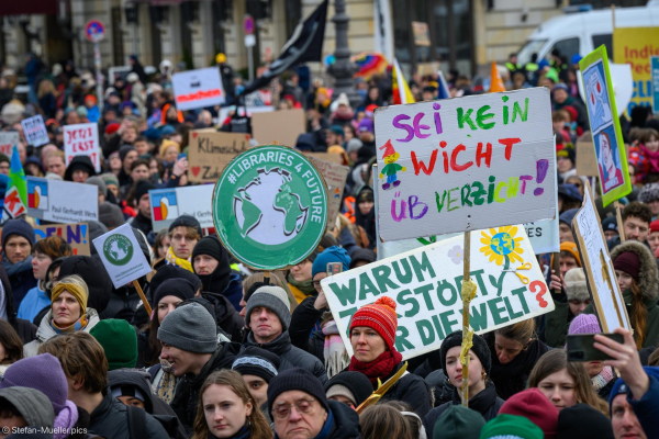 Schilder: „Libraries 4 future“ / „Sei kein Wicht üb Verzicht!“ beim Klimastreik von Fridays for Future. Am linken Bildrand Henning Jeschke und Lina Eichler, ehemeals Letzte Generation, Brandenburger Tor, Berlin, 14.02.2025