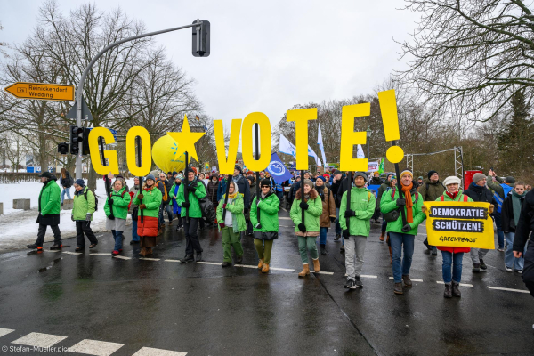 Teilnehmer von Greenpeace mit Schildern: „Go vote! Demokratie schützen!“. Beim Klimastreik von Fridays for Future vor der Bundestagswahl, Berlin, 14.02.2025